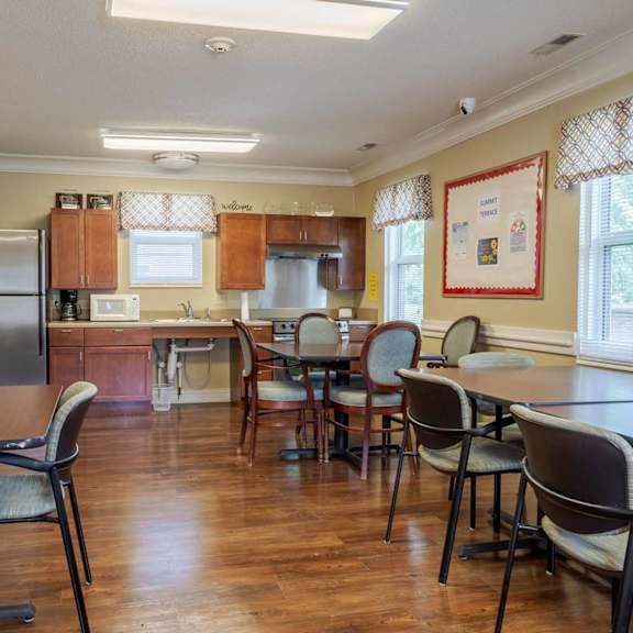 a kitchen with a table and chairs in the foreground and a refrigerator in the background.