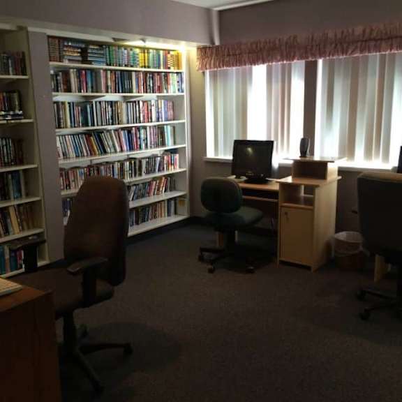 a room with a large bookshelf filled with books and a desk with a computer.