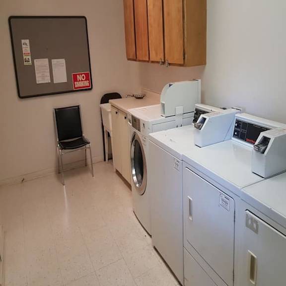 a laundry room with a washer and dryer, a black chair, and a sign on the wall.