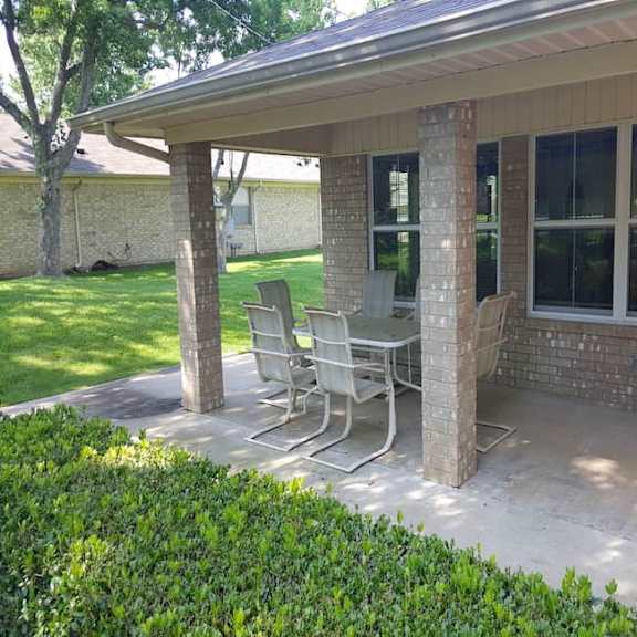 a patio with a table and chairs is covered by a roof.