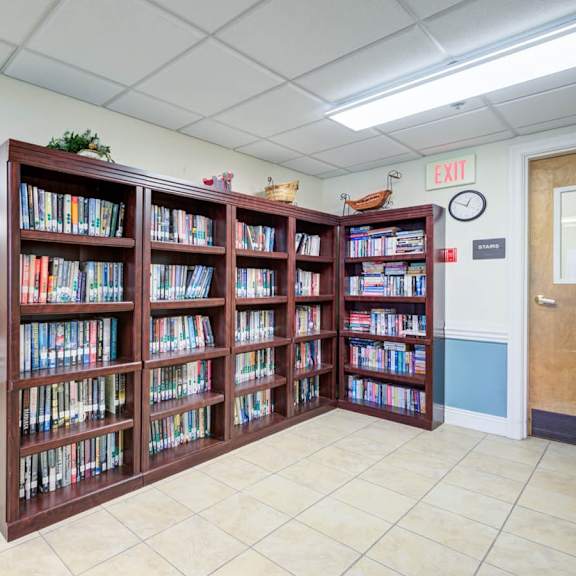 a room with a large bookcase filled with books and a clock on the wall.