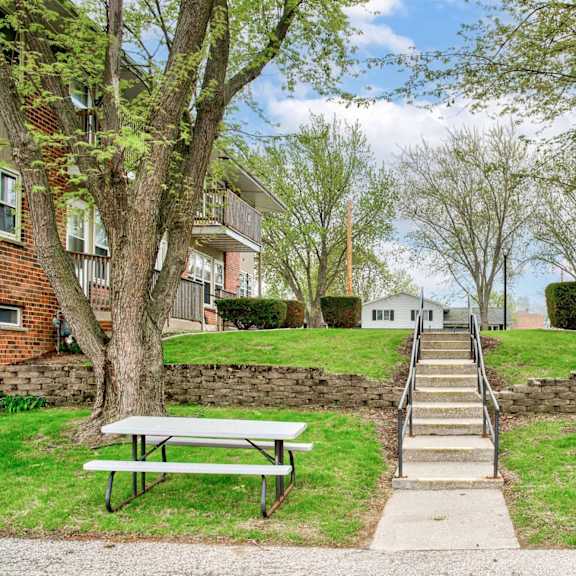 a park with a bench, trees and a stone wall.