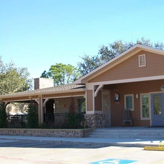 a small building with a brown roof and a stone wall in front.
