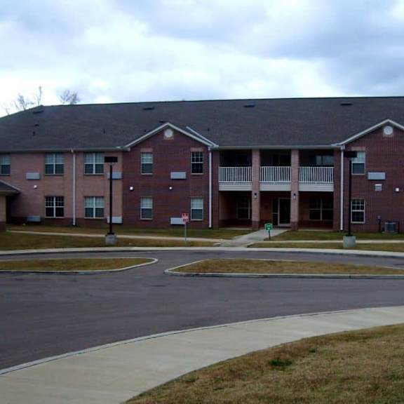 a large red brick apartment building with a grey roof.