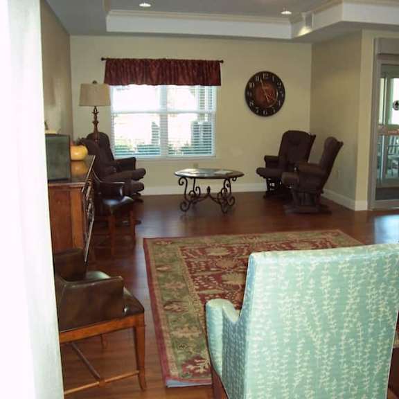 a living room with a green chair and a clock on the wall.