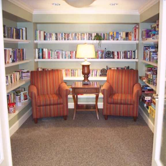 a room with a table, two chairs and a bookshelf.