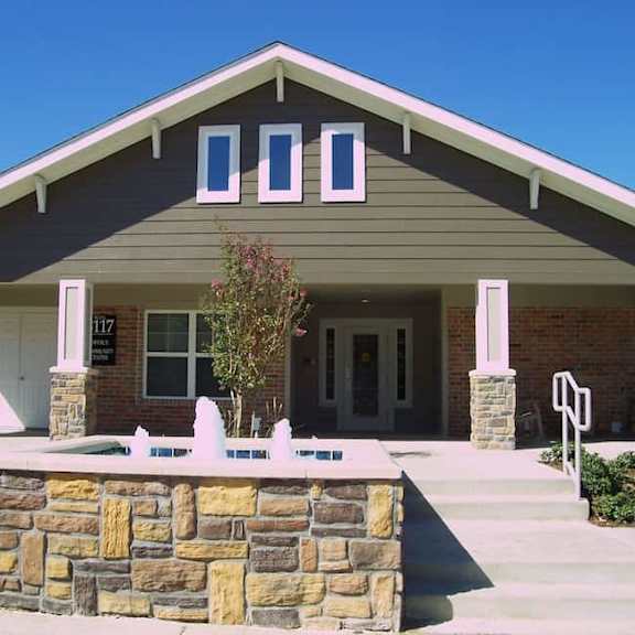 a house with a stone wall in front.