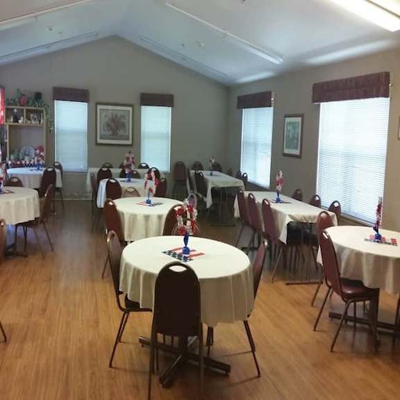 a room with tables and chairs and a coca-cola fridge.