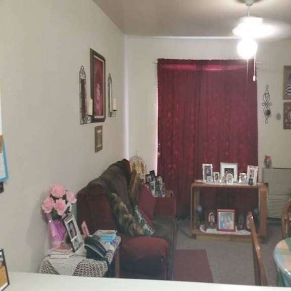 a living room with a red curtain and a table with a vase of flowers.