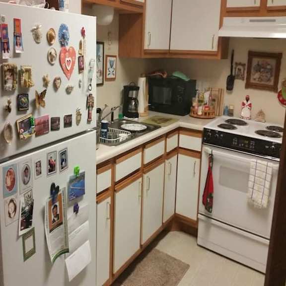 a kitchen with a refrigerator covered in magnets and a stove with a pot on it.