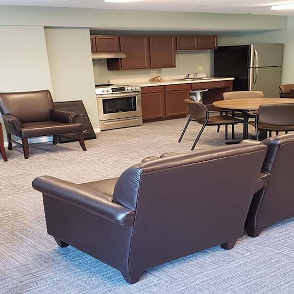 a living room with brown leather furniture and a kitchen in the background.