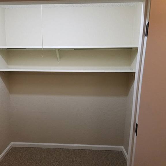 a white empty pantry with a door open.