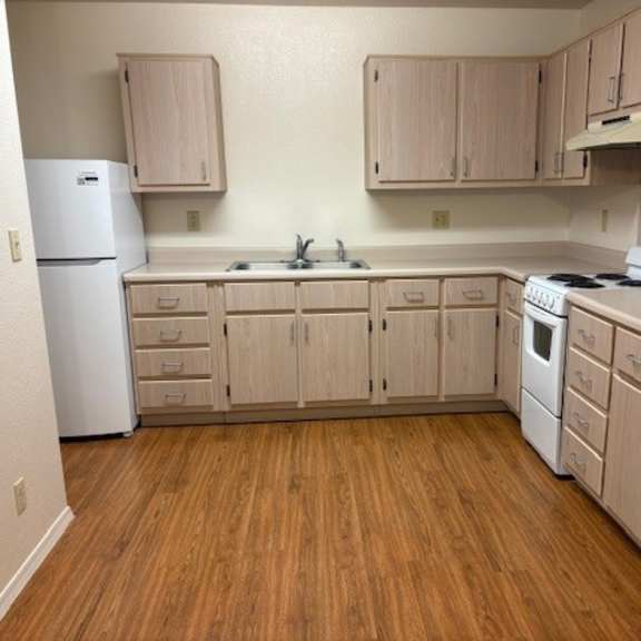 a kitchen with wooden floors and white appliances.