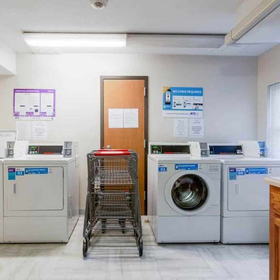 a laundry room with a washer and dryer, a shopping cart, and a sign on the wall.
