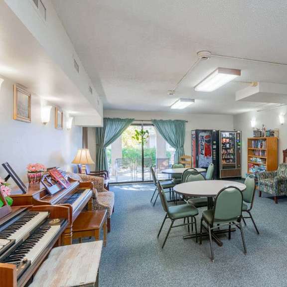 a room with a piano, chairs, and a television.