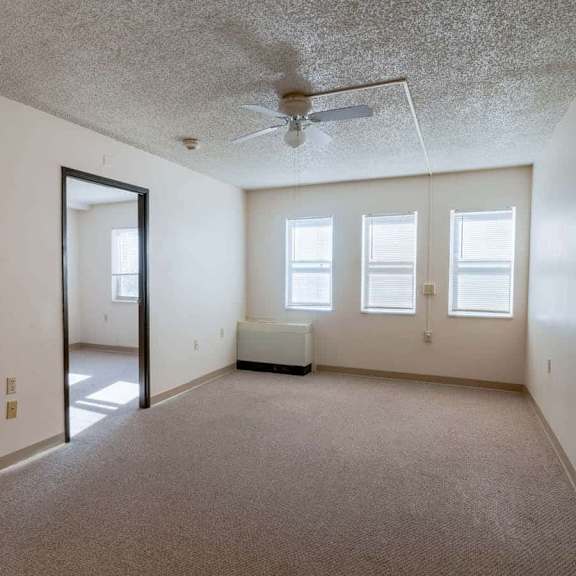 a spacious room with a carpeted floor, a ceiling fan, and a large mirror on the wall.