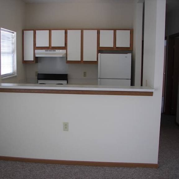 a kitchen with white appliances and wooden cabinets.