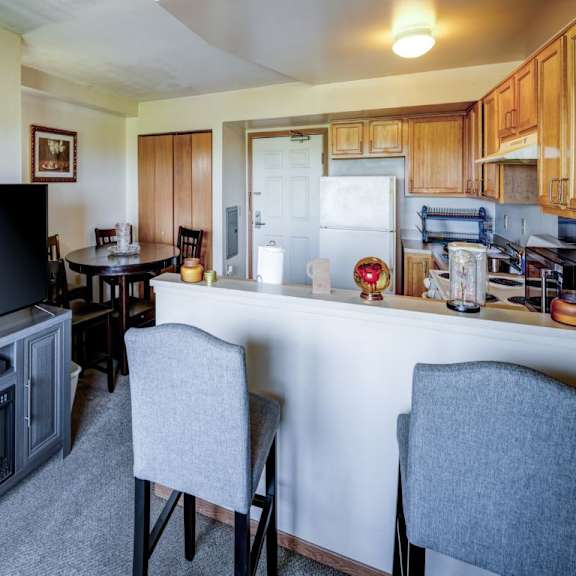 a kitchen with a table and chairs in the foreground and a refrigerator in the background.