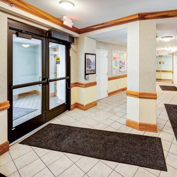 a hallway with a black carpet and a glass door.