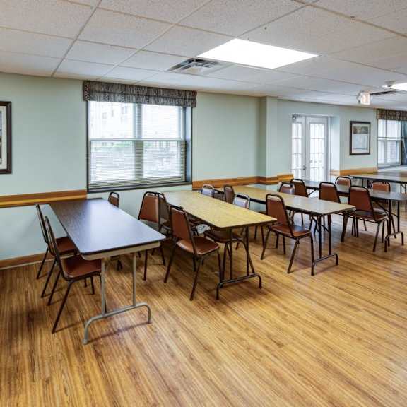 a room with wooden floors and tables with chairs.