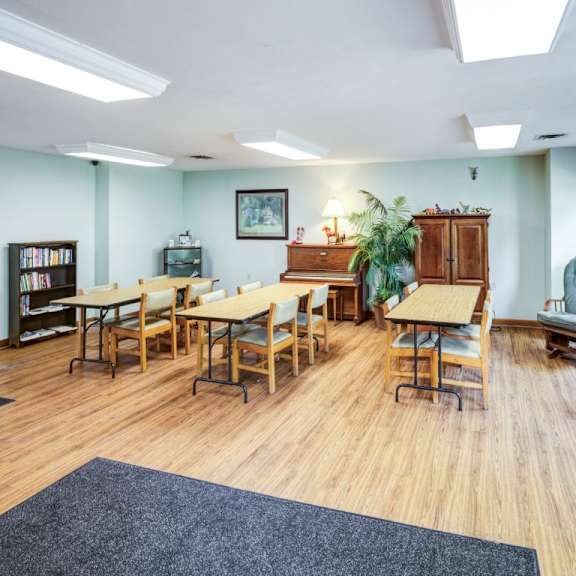 a room with wooden floors and furniture including a table, chairs, and a cabinet.