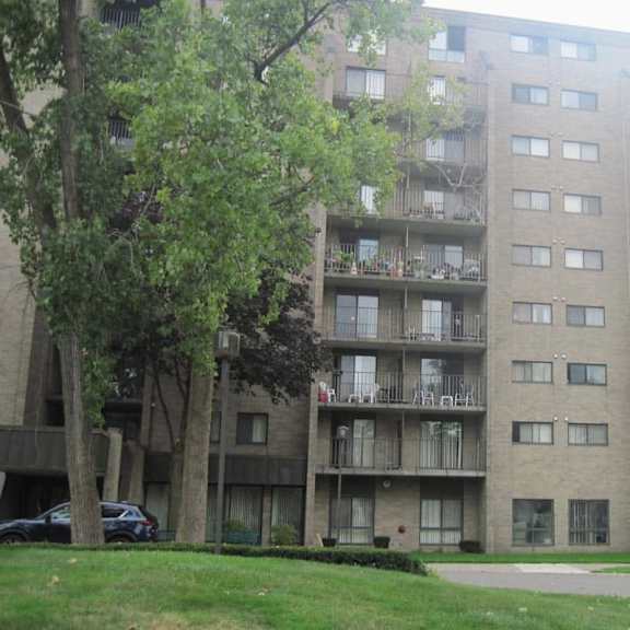 a tall apartment building with balconies and trees in front.