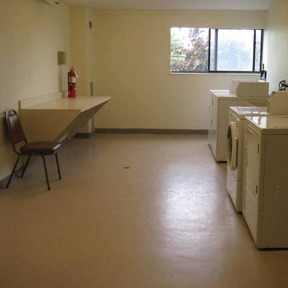 a laundry room with a washer and dryer, a bench, and a window.