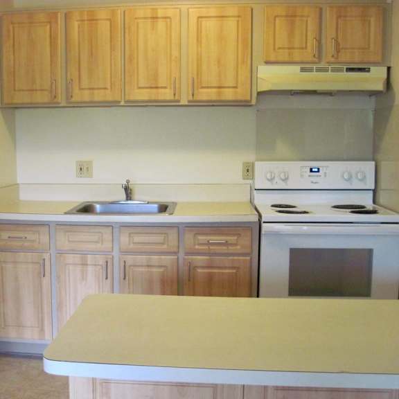 a kitchen with wooden cabinets and a white stove top oven.