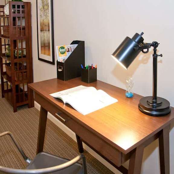 a desk with a lamp, a chair, and some papers on it.