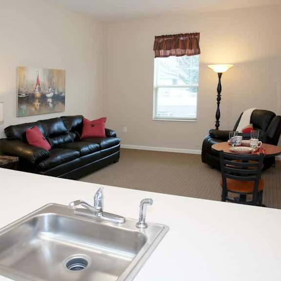a black leather couch sits in a living room with a small table and a lamp.
