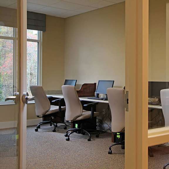 a room with a desk and chairs with a computer on it.
