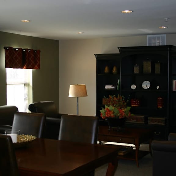 a brown table with chairs and a lamp in a room.