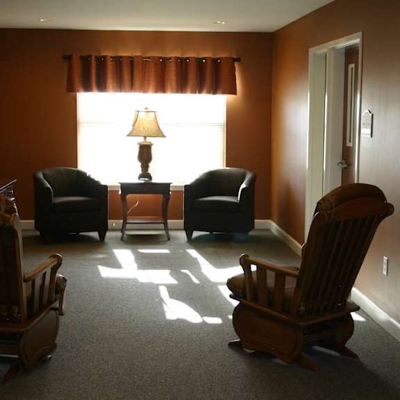 three wooden chairs are placed in a room with a table and a window.