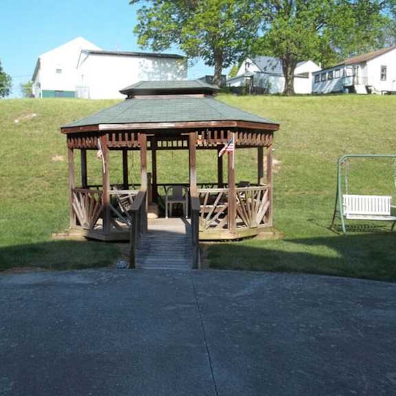 a gazebo with a flag on it is in the middle of a paved area.