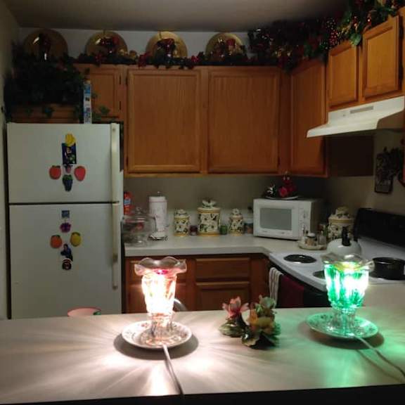 a kitchen with a white fridge and a green light on a table.