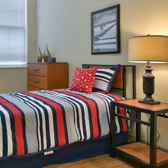 a bedroom with a bed, chair, and lamp.