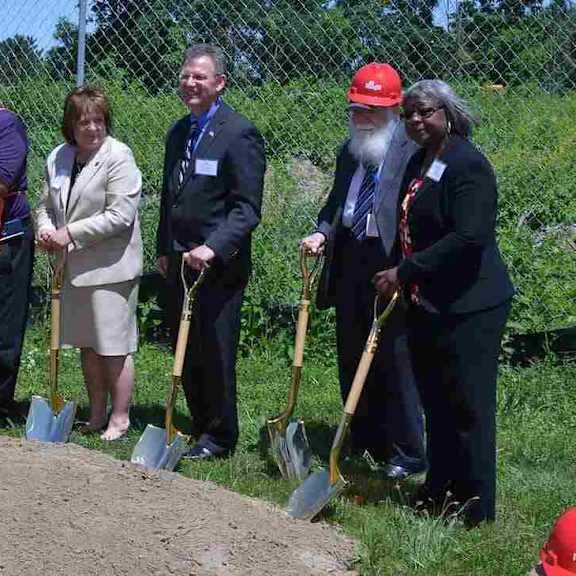 a group of people holding shovels at a groundbreaking ceremony.