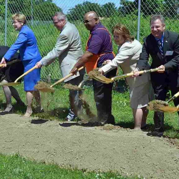 a group of people holding shovels at a groundbreaking ceremony.