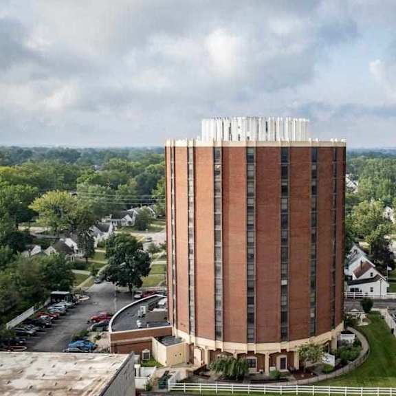 a tall brick building with the word "hytal" on top stands in the middle of a parking lot.