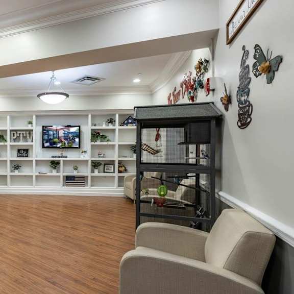 a living room with a grey sofa, a wooden floor, and a white wall with a clock on it.