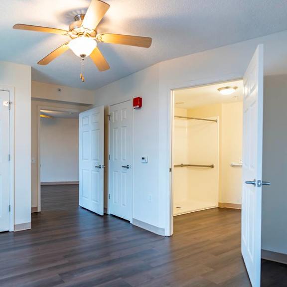 a room with a ceiling fan and white doors.
