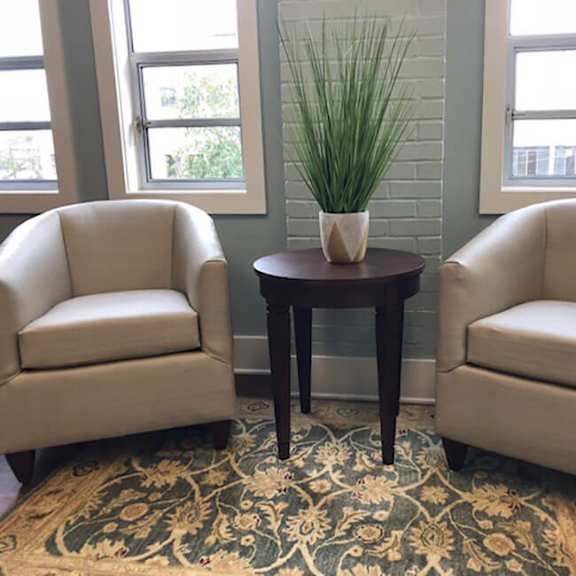 two chairs and a table with a potted plant on it.