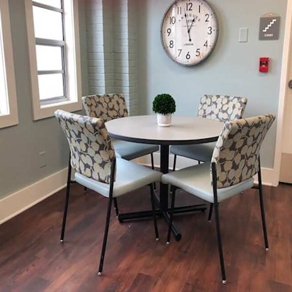 a table with four chairs and a clock on the wall.
