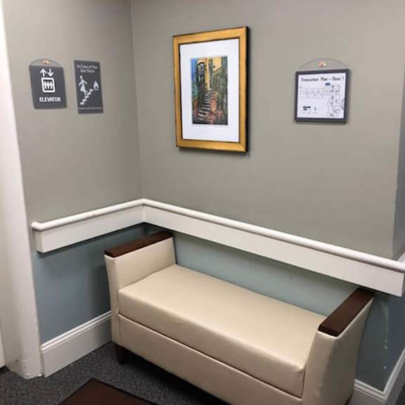 a white bench with a brown cushion is in the corner of a room.