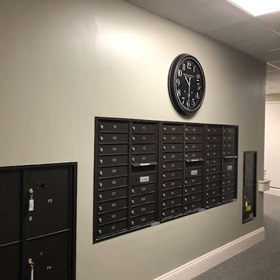 a wall with a clock and mailboxes.
