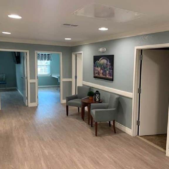 a hallway with a grey armchair and a painting on the wall.