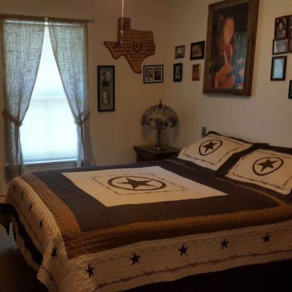 a bedroom with a texas-themed bedspread and a wooden state of texas decoration on the wall.