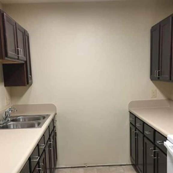 a kitchen with white countertops and dark brown cabinets.