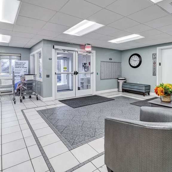 a reception area with a grey sofa, a black coffee table, and a clock on the wall.