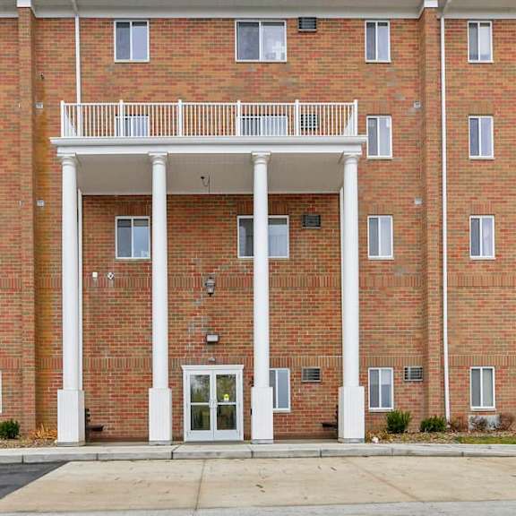 a red brick building with a white entrance and a balcony.